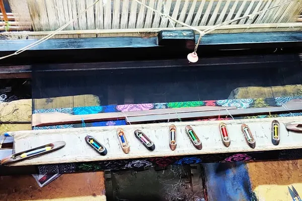Traditional loom set up with coloured weaving shuttles, used to handweave Songket fabric at the SongketTiger factory.