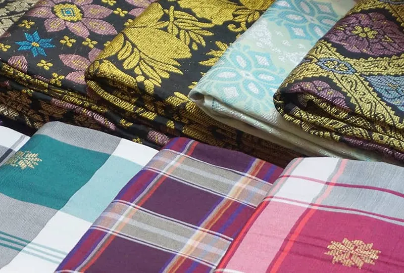 Folded machine-made Sampin fabrics in checked and floral woven patterns.